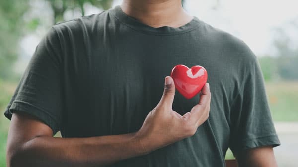 Homme tenant un coeur rouge contre son coeur